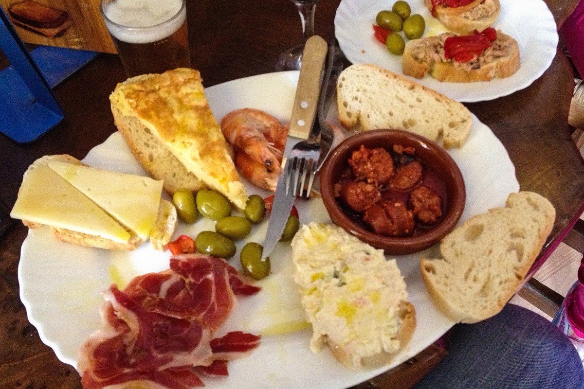 A plate of Spanish tapas with jamon, chorizo, olives and bread