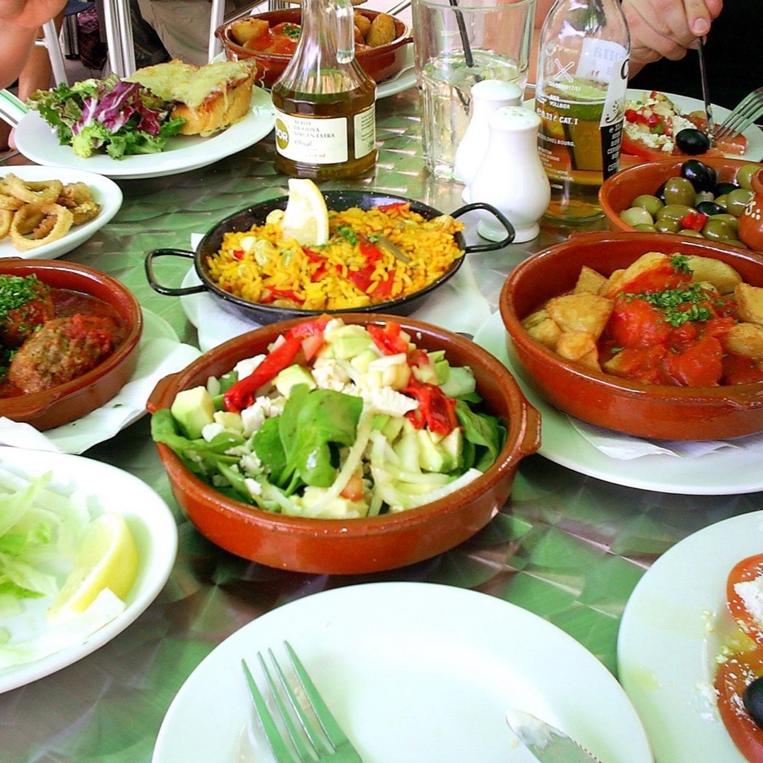 Friends sharing a spread of tapas dishes together around a table