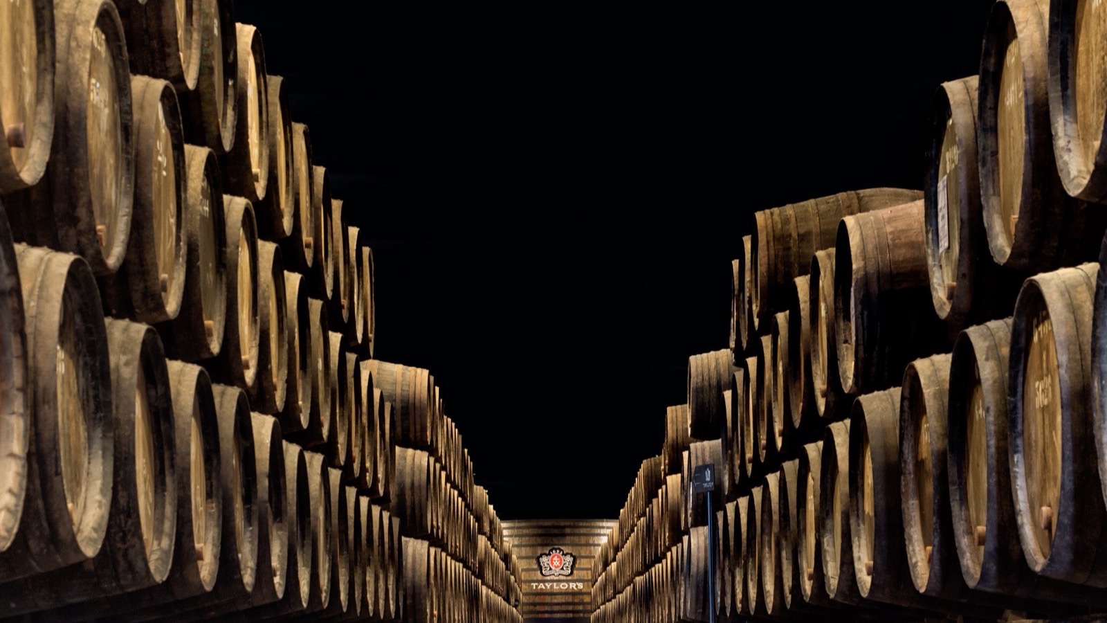 Rows of oak ageing barrels in an atmospheric Port wine cellar in Vila Nova de Gaia